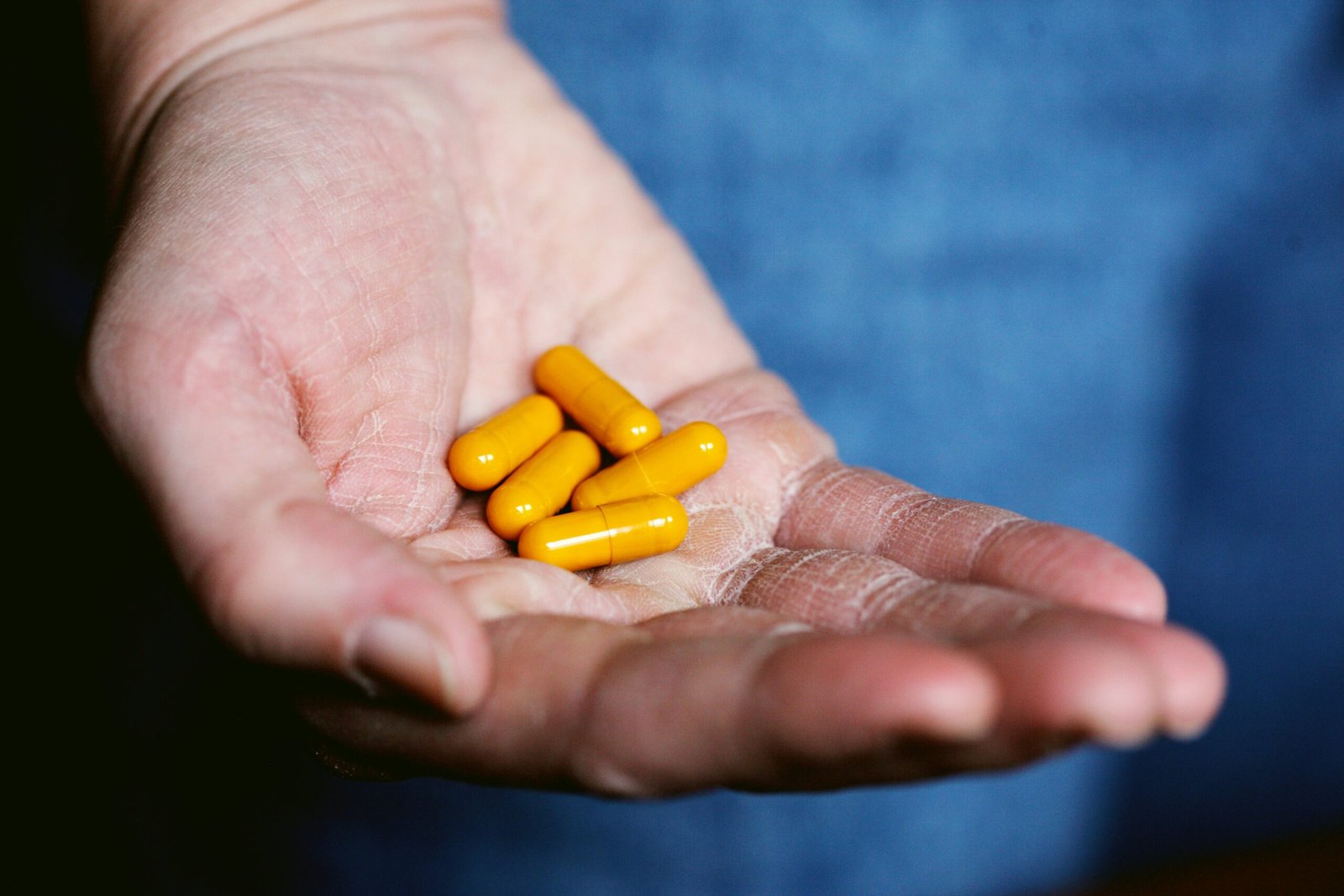 yellow medication pill on persons hand